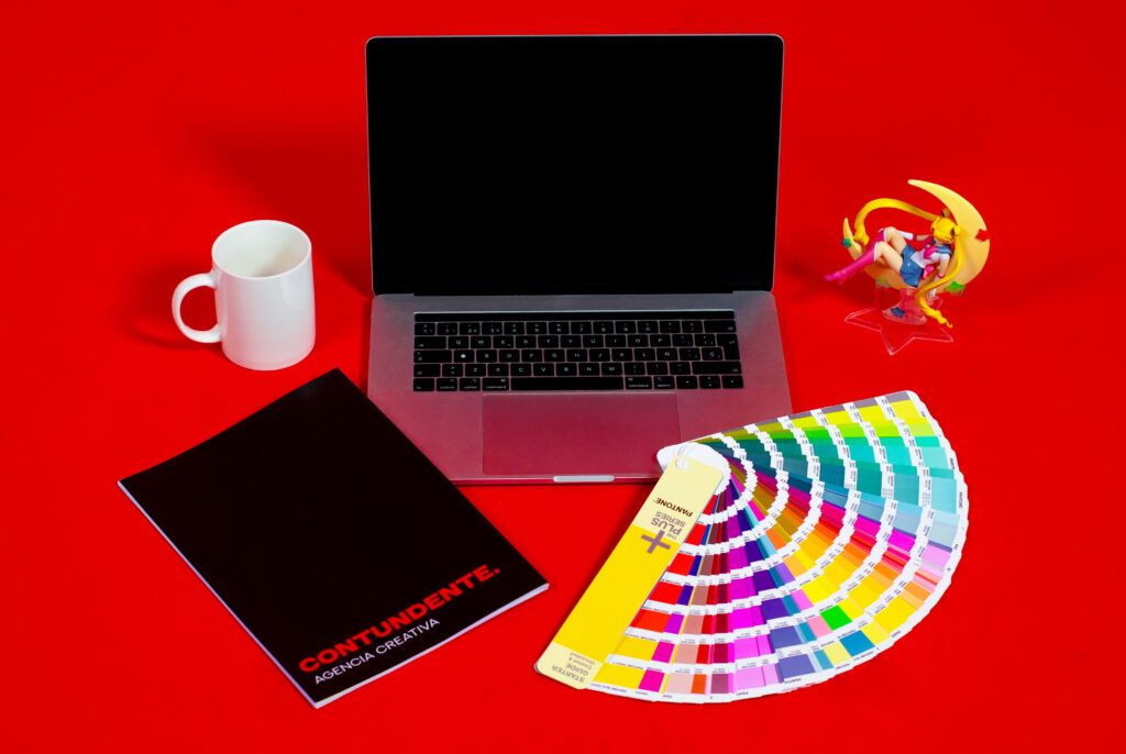 Un portatil, una taza, una revista de la agencia Contundente, una pantonera y una figura de Sailormoon. Decoración para una diseñadora gráfica